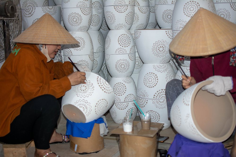 Artisans finishing white pierced pots